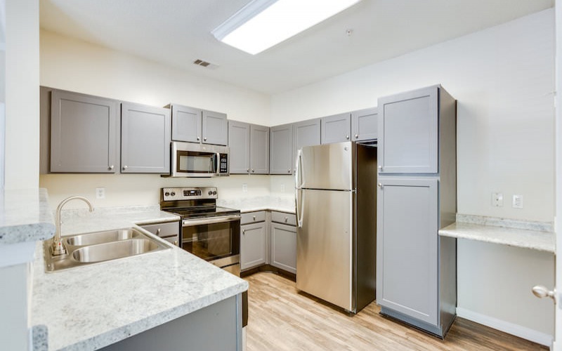 Spacious and well lit kitchen with wood floors and stainless steel appliances with access to the living room 